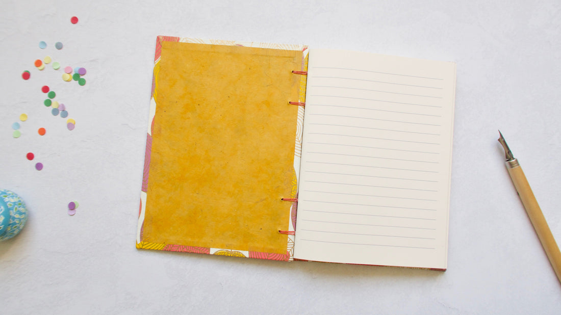 Carnet artisanal ouvert à plat avec confettis et porte-plume - L'atelier Reliure