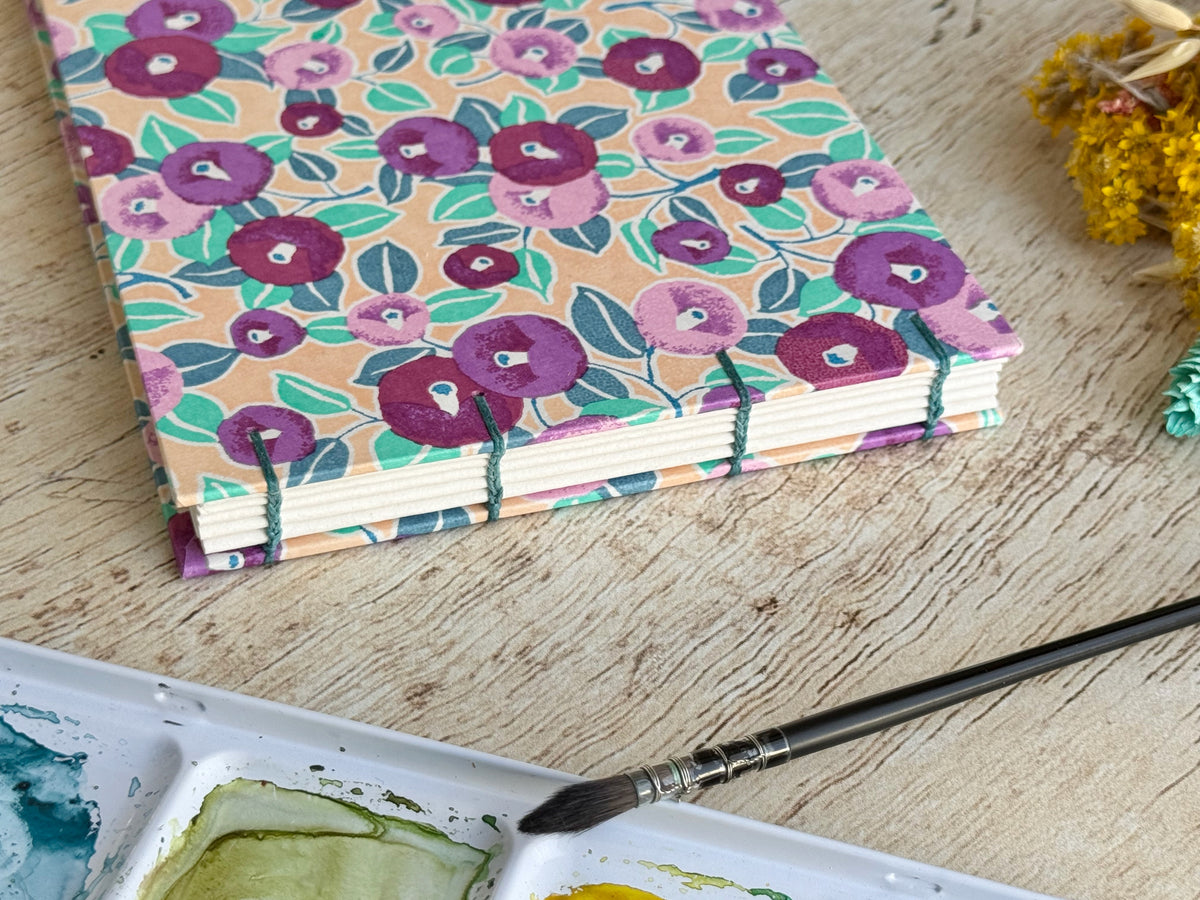 Carnet d'aquarelle découverte avec sa reliure copte et sa couverture en papier japonais motifs camélias violet et rose