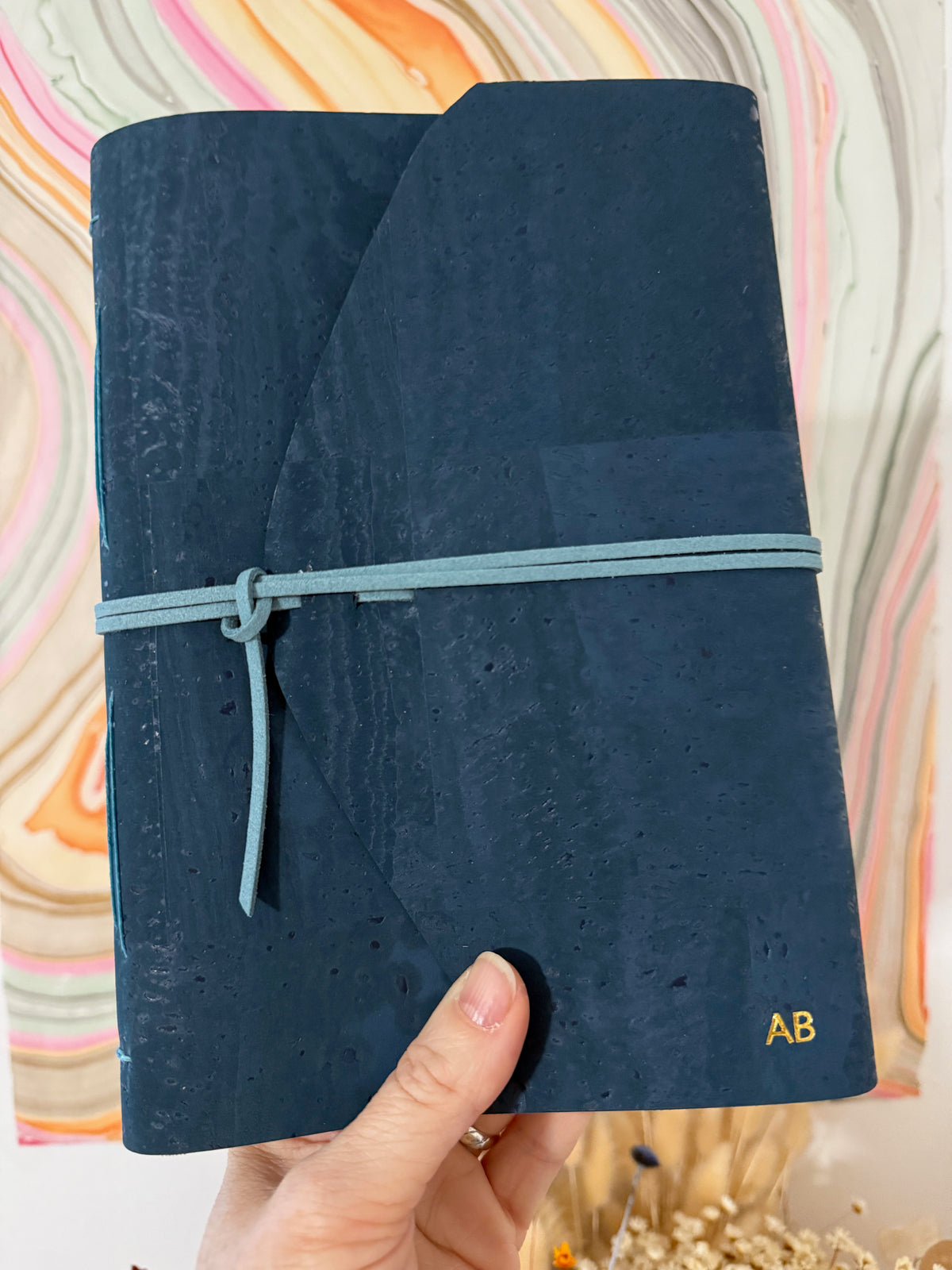 Initiales dorées personnalisées en bas à droite sur une couverture en liège bleu